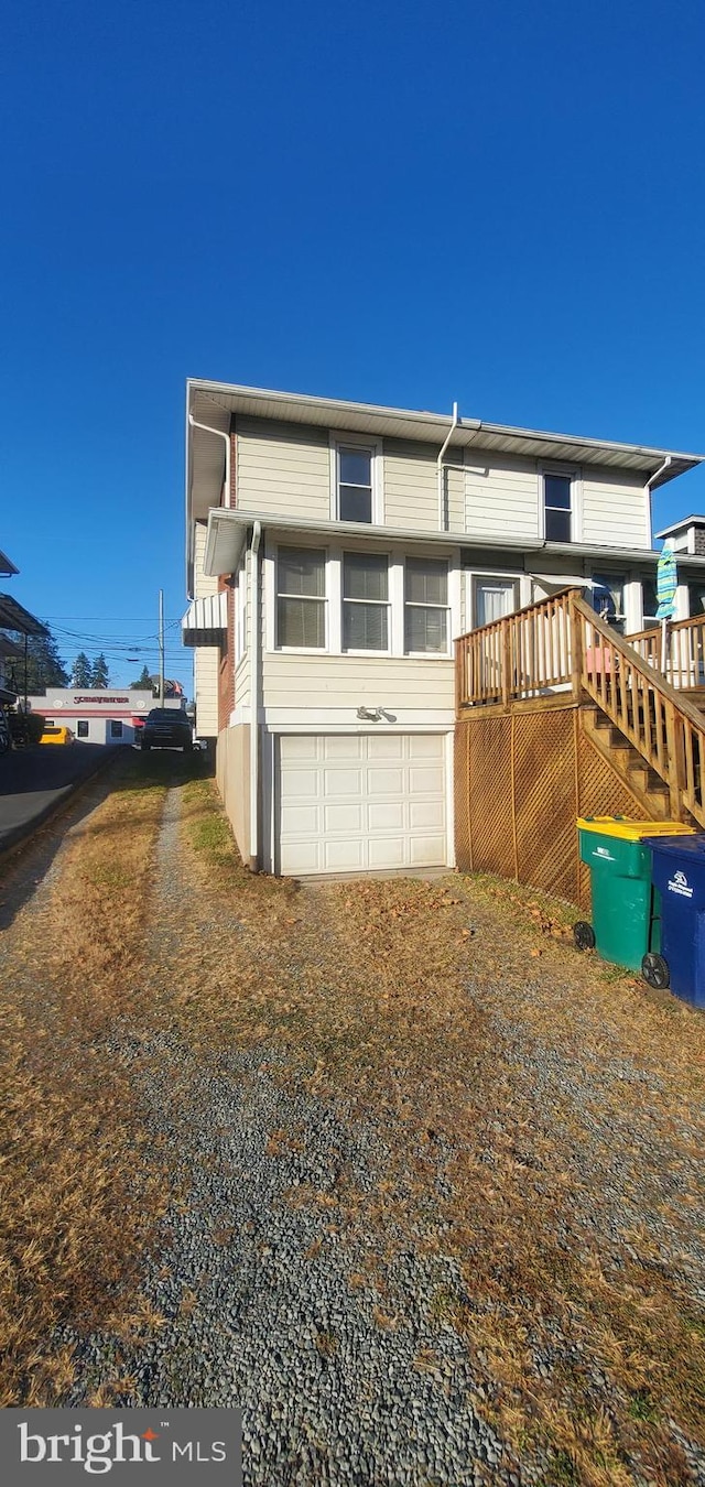 view of side of home with a sunroom, a garage, and a wooden deck