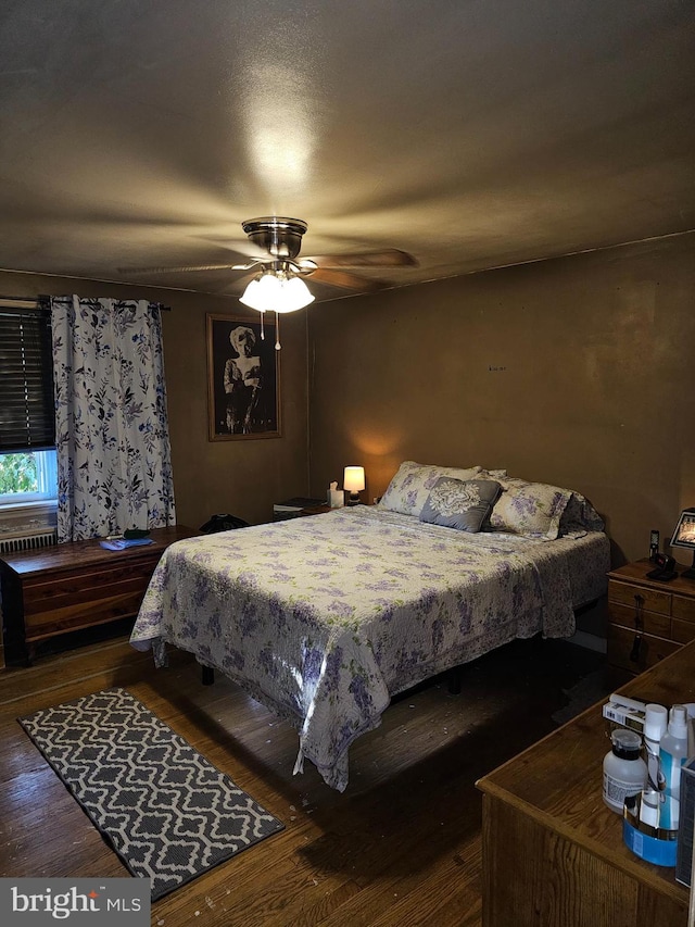 bedroom with dark hardwood / wood-style flooring and ceiling fan