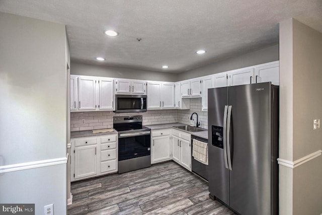 kitchen featuring white cabinetry, sink, stainless steel appliances, dark hardwood / wood-style floors, and decorative backsplash