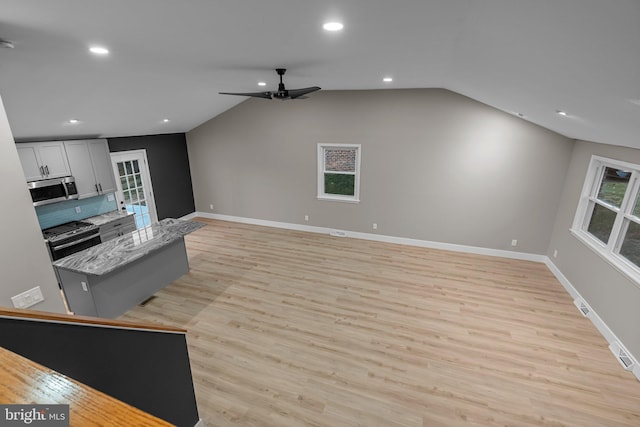 kitchen with plenty of natural light, light wood-type flooring, light stone countertops, and appliances with stainless steel finishes