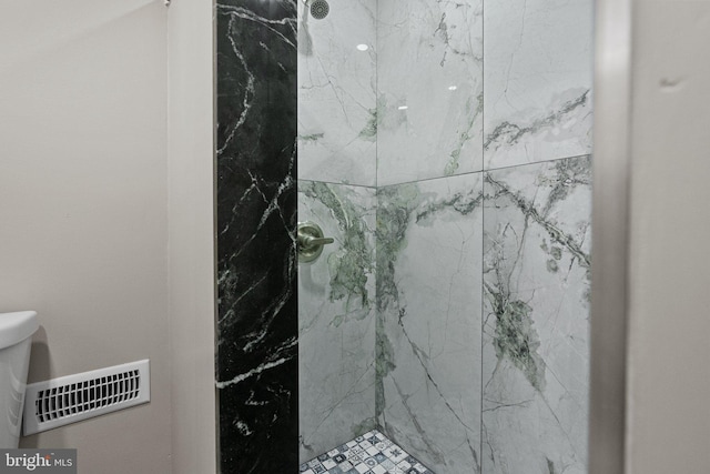 bathroom featuring a tile shower and toilet