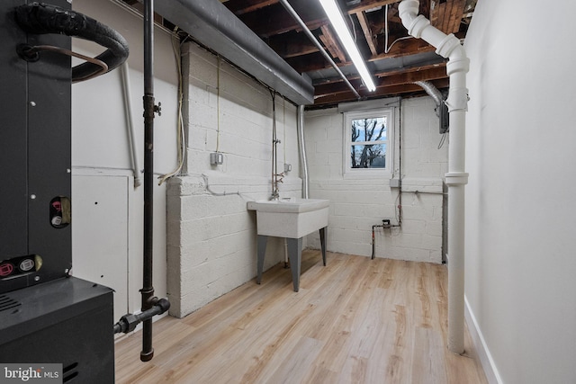 basement featuring heating unit and light hardwood / wood-style flooring