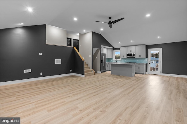 unfurnished living room featuring ceiling fan, light hardwood / wood-style flooring, vaulted ceiling, and sink