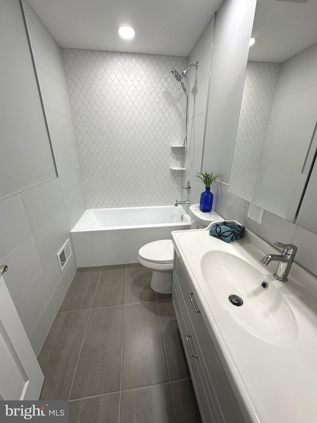 full bathroom with vanity, tile walls, tile patterned flooring, toilet, and tiled shower / bath