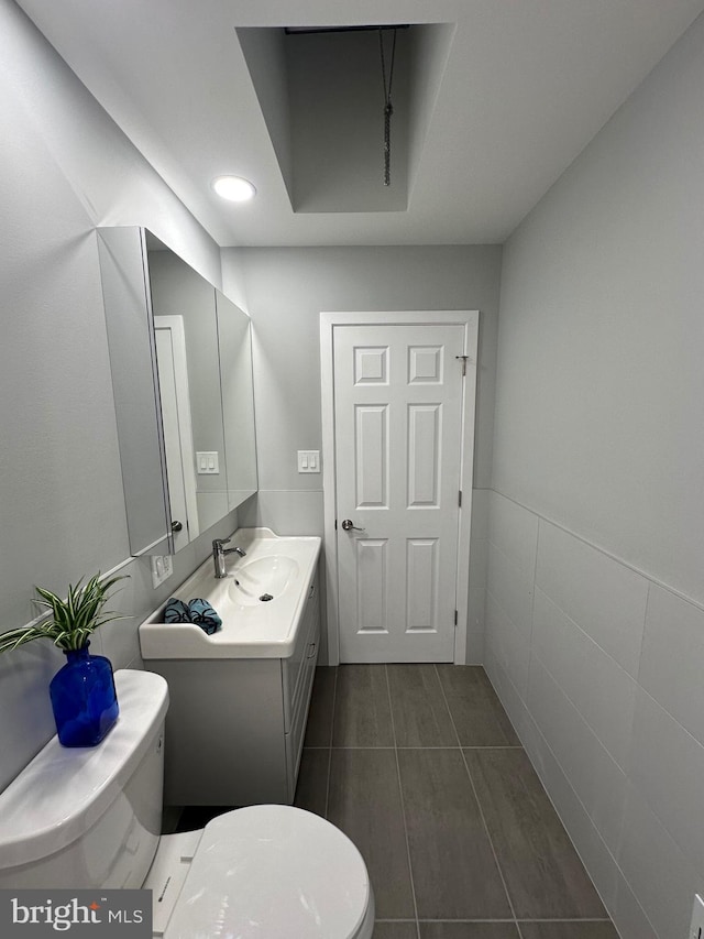 bathroom with tile patterned floors, vanity, toilet, and tile walls