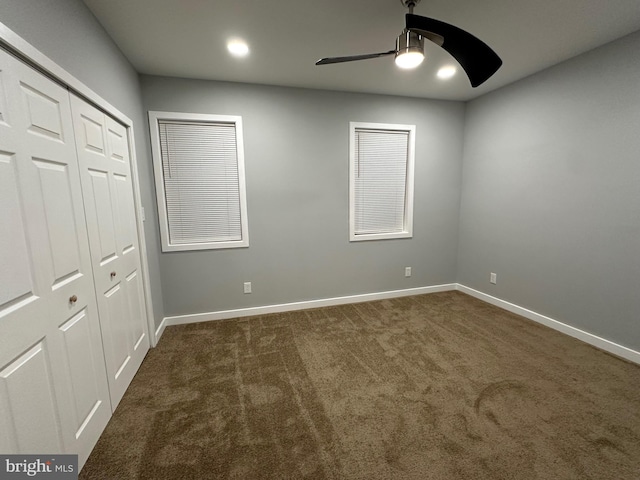 unfurnished bedroom featuring dark colored carpet, a closet, and ceiling fan