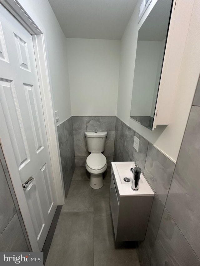 bathroom with vanity, toilet, and tile walls