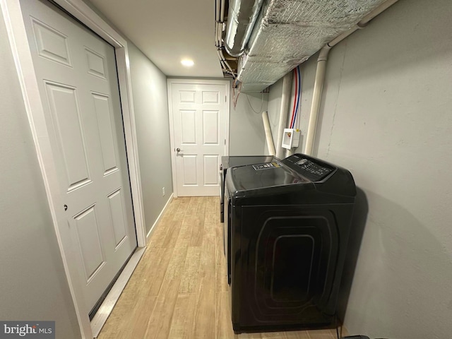 washroom with washing machine and clothes dryer and light hardwood / wood-style floors