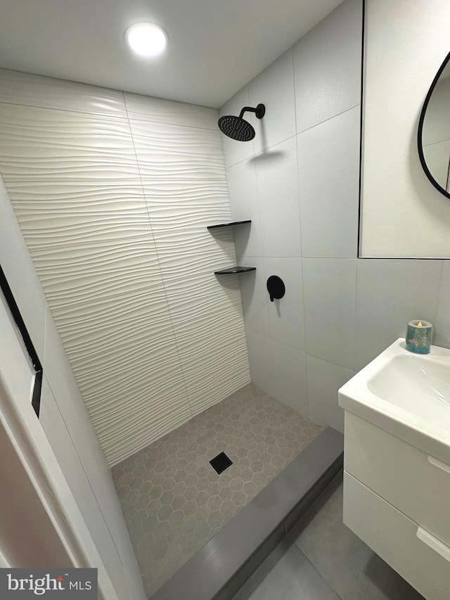 bathroom featuring vanity, a tile shower, and tile walls