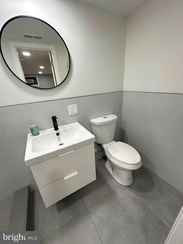 bathroom featuring vanity, tile walls, and toilet