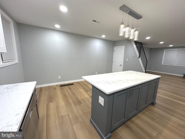 kitchen featuring pendant lighting, a kitchen island, light wood-type flooring, and an inviting chandelier