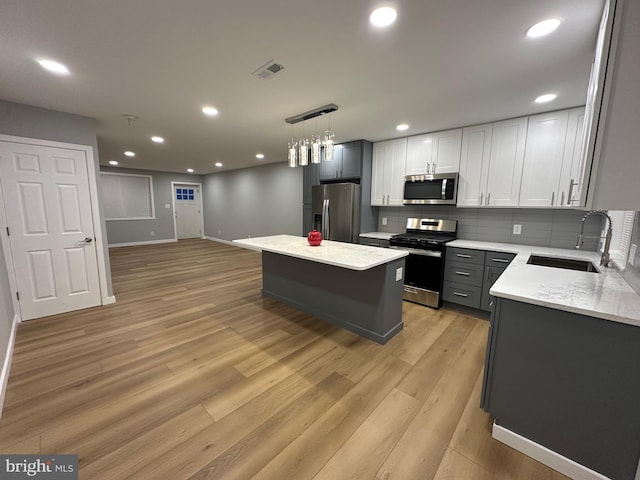 kitchen featuring hanging light fixtures, a kitchen island, light hardwood / wood-style floors, and appliances with stainless steel finishes