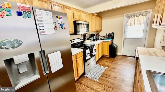 kitchen with sink, light brown cabinets, stainless steel appliances, and light hardwood / wood-style floors