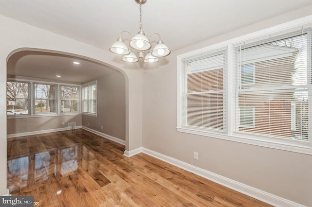 unfurnished dining area with a chandelier and wood-type flooring