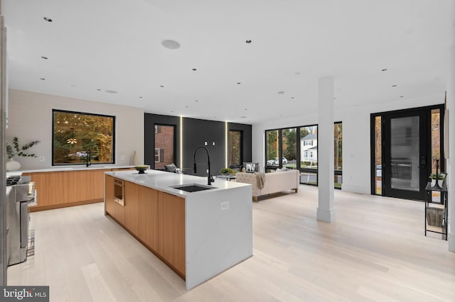 kitchen with sink, a spacious island, stainless steel range oven, and light hardwood / wood-style flooring