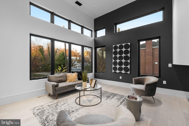 living room featuring a healthy amount of sunlight, a high ceiling, and light hardwood / wood-style flooring