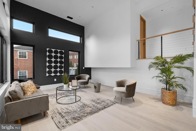 living room with a high ceiling, light hardwood / wood-style flooring, and plenty of natural light