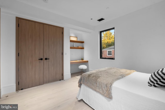 bedroom with built in desk and light hardwood / wood-style flooring