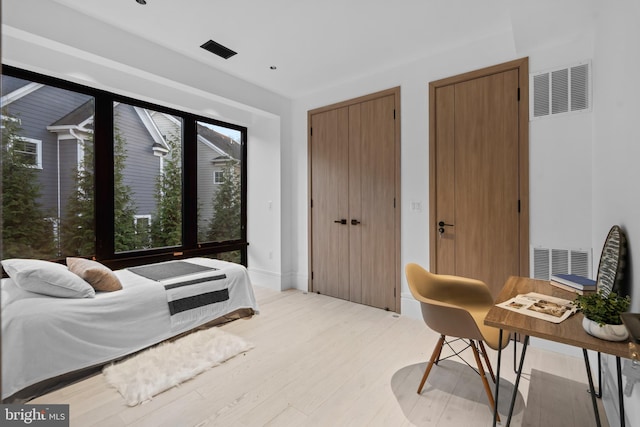 bedroom with light hardwood / wood-style flooring and multiple closets