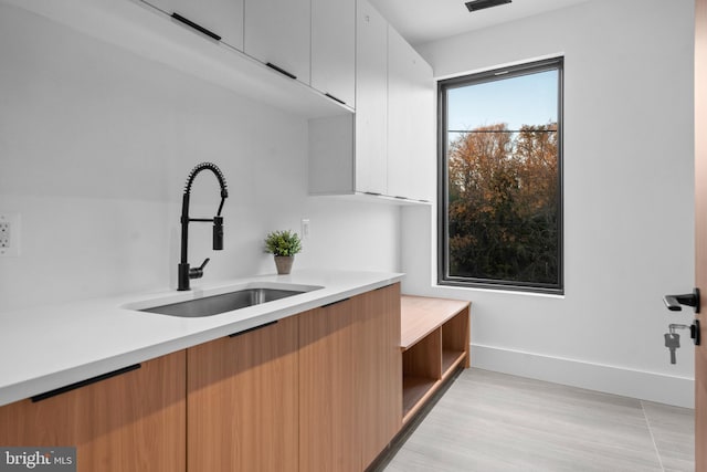 kitchen with light hardwood / wood-style flooring, white cabinetry, and sink