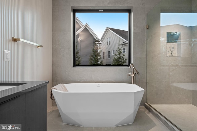 bathroom featuring plus walk in shower, vanity, and tile patterned flooring