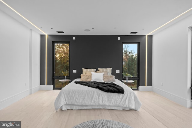 bedroom with light hardwood / wood-style floors and multiple windows