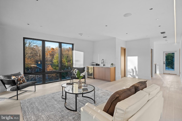 living room featuring light hardwood / wood-style floors, wine cooler, and sink