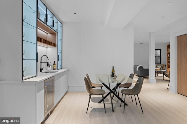 dining space with light wood-type flooring, sink, and wine cooler