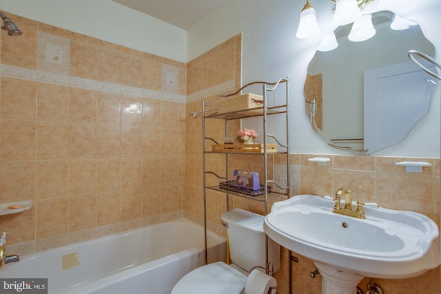 full bathroom with sink, tiled shower / bath combo, toilet, and tile walls