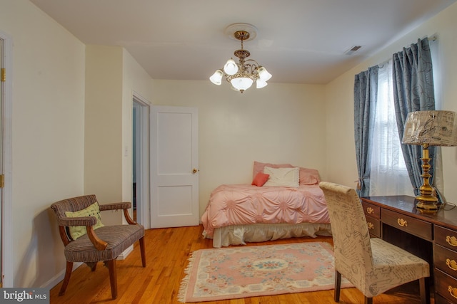 bedroom with a notable chandelier and light wood-type flooring