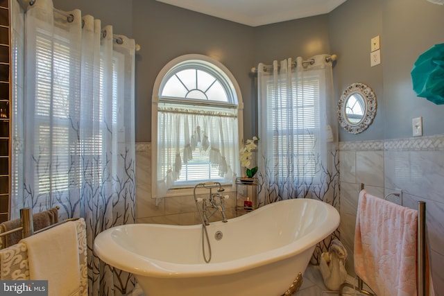 bathroom with tile patterned flooring, a tub to relax in, and tile walls