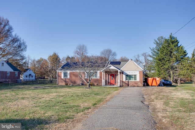 ranch-style home with solar panels and a front lawn