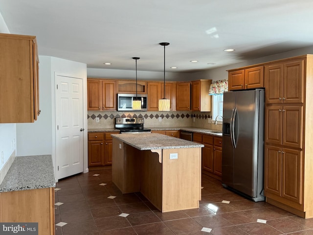 kitchen featuring light stone countertops, a kitchen island, decorative light fixtures, and appliances with stainless steel finishes