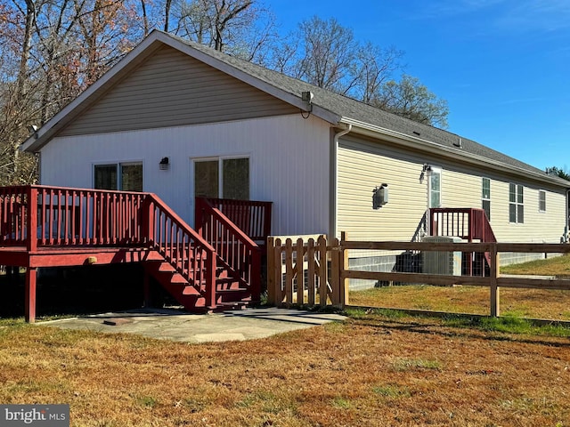 rear view of house featuring a lawn and a wooden deck