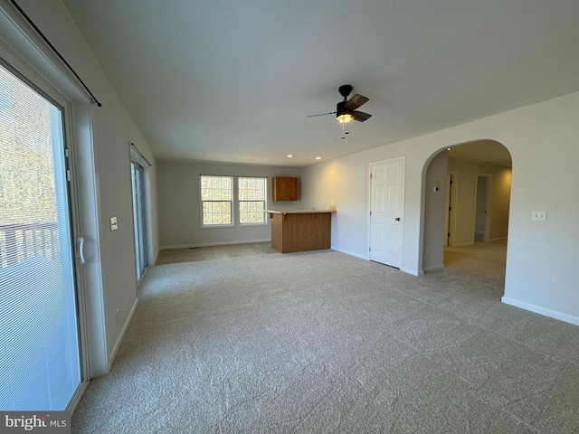 unfurnished living room featuring light carpet and ceiling fan