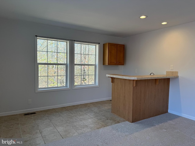 kitchen featuring a kitchen breakfast bar, kitchen peninsula, and light carpet