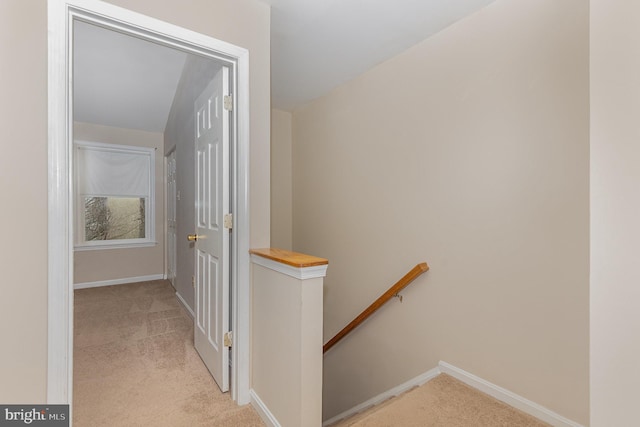 hall featuring baseboards, light colored carpet, and an upstairs landing