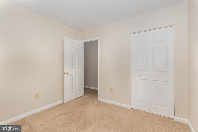 unfurnished bedroom with baseboards, a closet, and light colored carpet