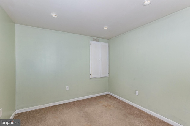 spare room with recessed lighting, light colored carpet, and baseboards