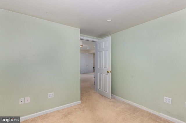 spare room featuring baseboards and light colored carpet