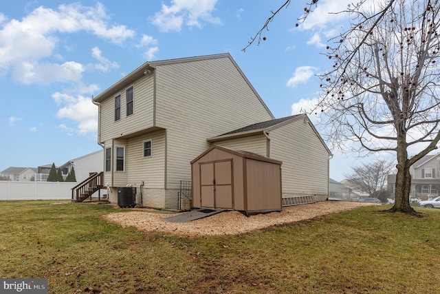 rear view of property with an outbuilding, central air condition unit, fence, a yard, and a shed