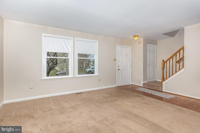 foyer entrance featuring stairway, carpet flooring, visible vents, and baseboards