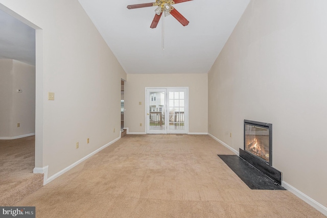 unfurnished living room featuring high vaulted ceiling, carpet flooring, a fireplace with flush hearth, a ceiling fan, and baseboards