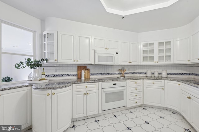 kitchen with white appliances, white cabinetry, and backsplash