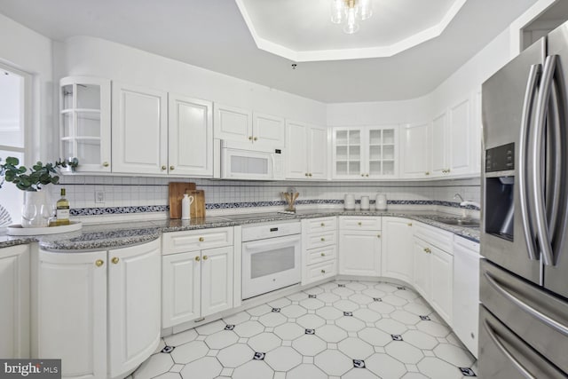 kitchen featuring backsplash, white cabinets, and white appliances