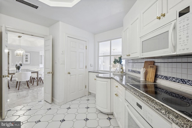 kitchen featuring white appliances, white cabinets, tasteful backsplash, decorative light fixtures, and a chandelier