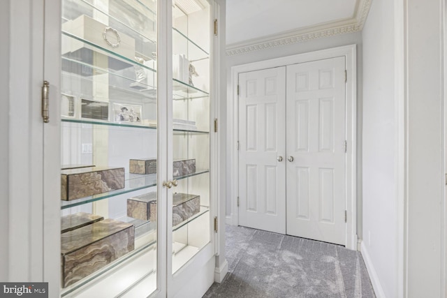 interior space featuring dark colored carpet and ornamental molding