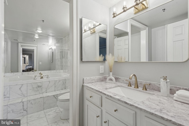 bathroom featuring vanity, toilet, and tiled bath