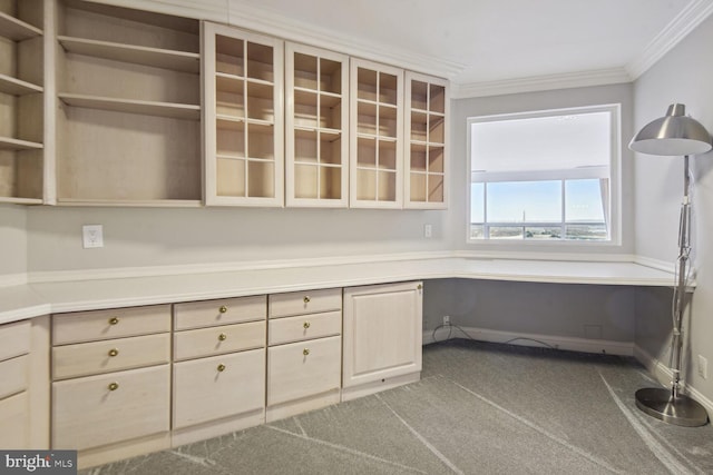 unfurnished office with carpet, built in desk, and crown molding