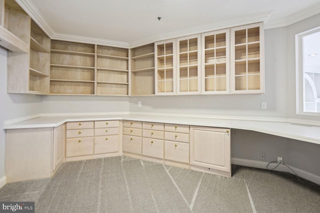 unfurnished office featuring built in desk, carpet floors, and crown molding